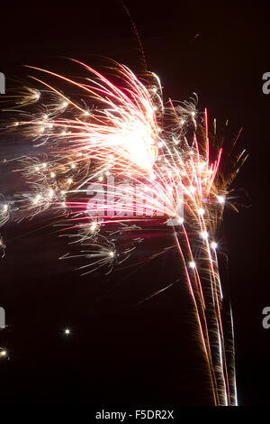 Feuerwerk am Lagerfeuer platzen / Kerl Fawkes Nacht mit Streifen von rosa und blass Orange und knistert und funkelt. Stockfoto