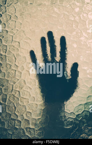 die Hand hinter dem Glas Stockfoto