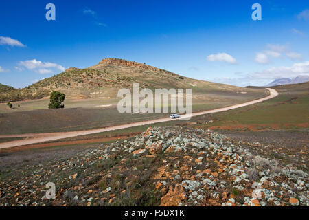 Fahrzeug auf langen Weg über karge steinige Landschaft & Hills von Flinders reicht Nat Pk unter blauem Himmel im Outback South Australia Stockfoto