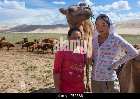 Nomadische Hirten Kamele, mit zwei Buckel baktrischen Kamel mit Khongoryn Els Sanddünen hinter, Wüste Gobi, Mongolei Stockfoto