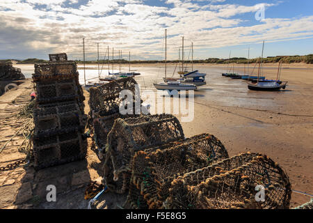 Hummer-Töpfe auf Hafenmauer und Yachten am Strand bei Ebbe auf einen Sommer Abend Beadnell, Northumberland, England, UK Stockfoto