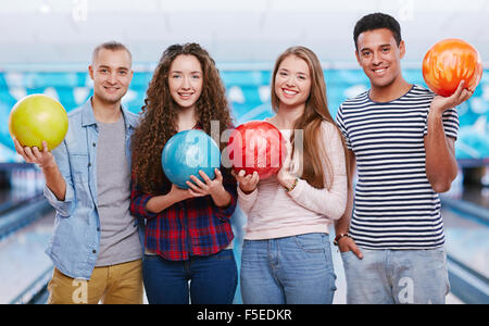 Junge Freunde mit Bowlingkugeln Blick in die Kamera Stockfoto