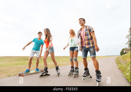 glückliche Jugendliche mit Rollerblades und longboards Stockfoto