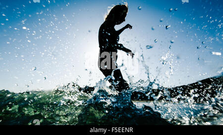 Silhouette einer Frau im Meer auf Surfbrett Stockfoto