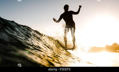 Frau Surfen bei Sonnenuntergang, Malibu, Kalifornien, USA Stockfoto