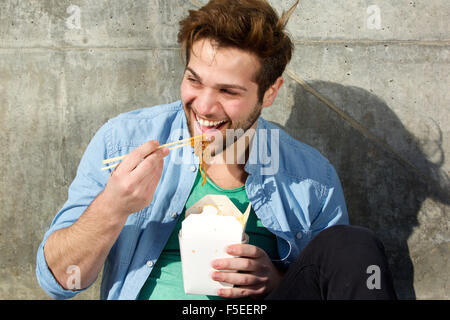 Porträt von ein glücklicher Mann Essen Essen mit Stäbchen Stockfoto