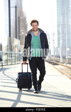 Ganzkörper-Porträt von ein glücklicher Mann zu Fuß am Bahnhof Bahnsteig mit Tasche Stockfoto