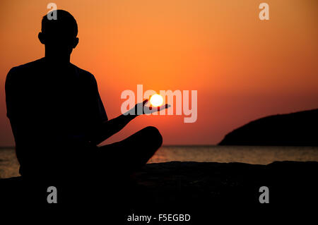 Silhouette eines Mannes, der mit der Sonne in der hand Stockfoto