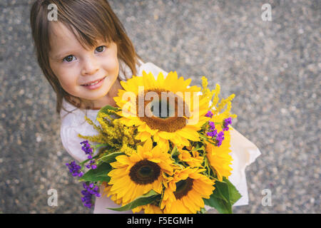 Draufsicht eines Mädchens mit Haufen von Sonnenblumen Stockfoto