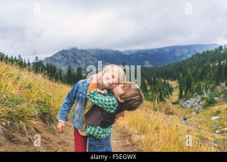 Zwei Brüder umarmen und küssen auf Bergpfad Stockfoto