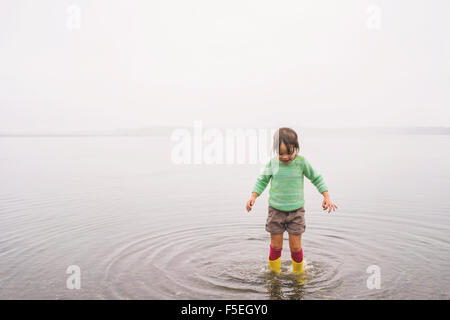 Mädchen stehen im flachen Wasser, Wellen machen Stockfoto