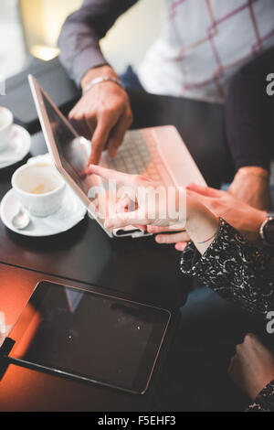 Nahaufnahme von einer Gruppe von Geschäftsleuten mit einem Treffen in einer Bar mit Laptop und Tablet - Geschäft, Teamarbeit, Multitasking, Technik, Konzepte - Fokus auf den Händen zu treffen Stockfoto