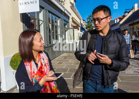 Paris, Frankreich, chinesisches Paar Shopping Luxusgeschäfte in 'La Vallee Village', Discounter, Asian mit Smartphones, iPhone auf der Straße (M.R.) Urlaub Stockfoto