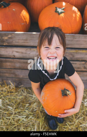 Lächelndes Mädchen hält einen riesigen Kürbis Stockfoto