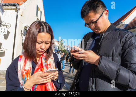 Paris, Frankreich, Chinesisches Paar Einkaufsläden in 'La Vallee Village', Rabattläden, Asiatisch mit Smartphones, iPhones on Street, frankreich Mobiltelefone Stockfoto