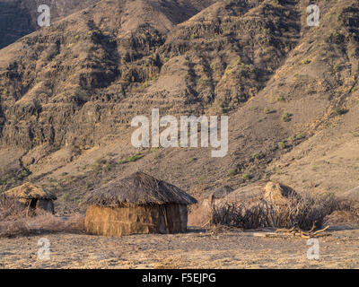 Traditionelles Haus in einem Massai-Dorf vor dem Oldoinyo Lengai in der Arusha Region in Tansania, Afrika, bei Sonnenaufgang. Stockfoto