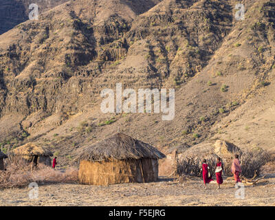 Drei Kinder zu Fuß in einem Massai-Dorf vor dem Oldoinyo Lengai in der Arusha Region in Tansania, Afrika, bei Sonnenaufgang. Stockfoto