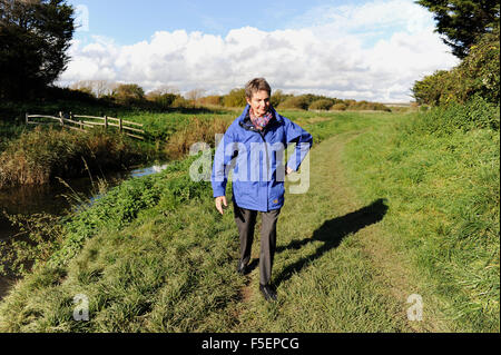 Älteren senior älteres Paar gehen für einen Spaziergang entlang dem Fluss weit verbreitet in Ferring in der Nähe von Worthing Sussex UK Stockfoto