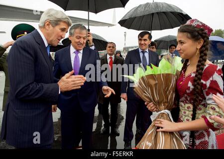 US-Außenminister John Kerry ist mit Blumen von Tradition kostümiert tadschikischen Mädchen als Tadschikistan Foreign Minister Sirodjiddin Muhriddinovich Aslov am Flughafen Duschanbe 3. November 2015 in Duschanbe, Tadschikistan blickt auf vorgestellt. Stockfoto