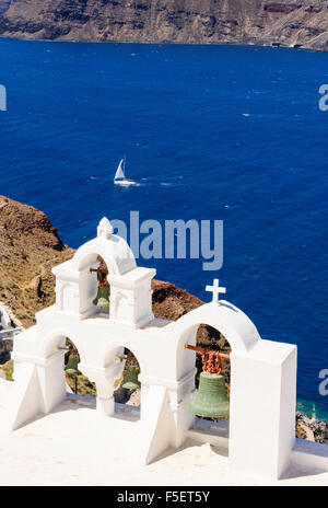 Eine Yacht segelt Bast der offenen Glockenturm einer weißen Kirche in Oia, Santorini, Kykladen, Griechenland Stockfoto