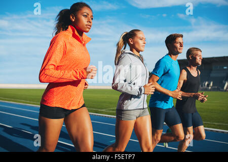 Gruppe von vielfältigen Sport Person üben im Stadion laufen. Männlichen und weiblichen Athleten zusammen auf Rennstrecke laufen. Stockfoto