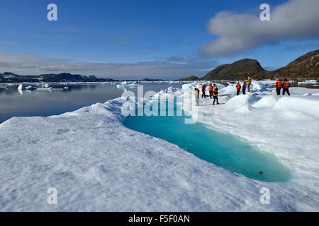 Gruppe von Menschen stehen auf einer Eisscholle oder Treibeis, Tunu Fjord, Kalaallit Nunaat, Ostgrönland Stockfoto