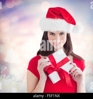 Zusammengesetztes Bild des festlichen Brünette Holding Geschenk Stockfoto