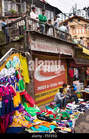 Stall niedriger Basar, jungen im Leerlauf auf Balkon über Kleidung, Shimla (Simla), Himachal Pradesh, Indien Stockfoto