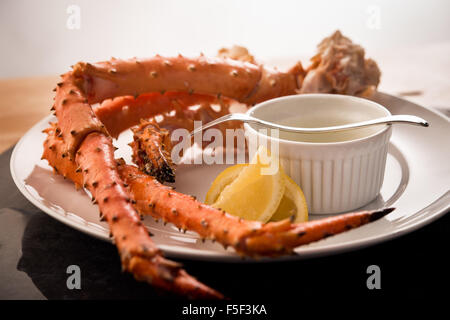 Königskrabbe Beine serviert mit Butter und einer Zitronenscheibe Stockfoto