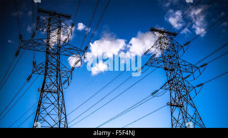 Hochspannungsleitungen und Türme in der Silhouette gegen Sonnenuntergang Himmel und Wolken Stockfoto
