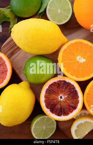 Gemischte Zitrusfrüchte einschließlich Nabel und Blut Orangen, Zitronen und Limetten auf dunklen Holztisch. Stockfoto