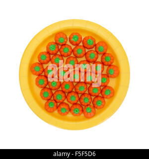 Draufsicht der orange und grün Halloween Kürbis Süßigkeiten auf eine gelbe Pappteller isoliert auf einem weißen Hintergrund. Stockfoto