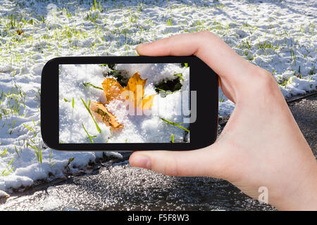 Saison Konzept - Mann unter Bild der erste Schnee am Rasen auf smartphone Stockfoto