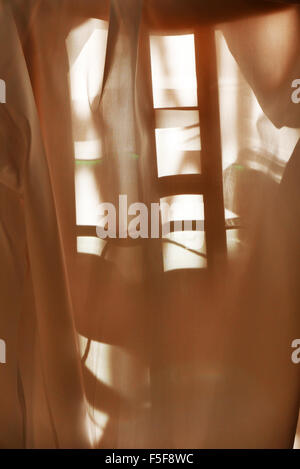 Am frühen Morgensonnenlicht durch Material über einen Stuhl gelegt. Stockfoto