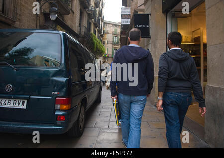 Zwei Männer in Jeans gehen durch die enge Einkaufsstraße am VW-Van in Barcelona Catalonia Spain es vorbei Stockfoto