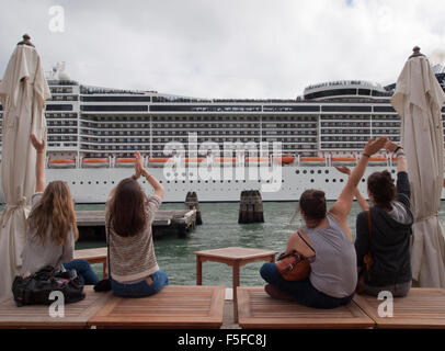 Zum verlassen Kreuzfahrtschiff MSC Divina verzichten Touristen sitzen am Canale della Giudecca in Venedig, Italien, auf. Stockfoto