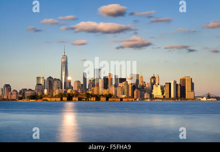 Skyline von New York City, Lower Manhattan. Ellis Island erscheint vor den Financial District Wolkenkratzer Stockfoto