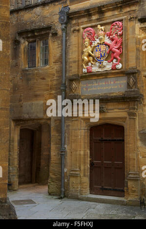 Einen kleinen abgeschiedenen Innenhof in Sherborne School. Über eine Tür ist das königliche Wappen von König Edward 6. Dorset, England, Vereinigtes Königreich. Stockfoto