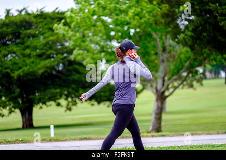 Eine Kaukasische Frau in ihren 30ern erzählt über ihr Handy während des Trainings in einem öffentlichen Park in Oklahoma City, Oklahoma, USA. Stockfoto