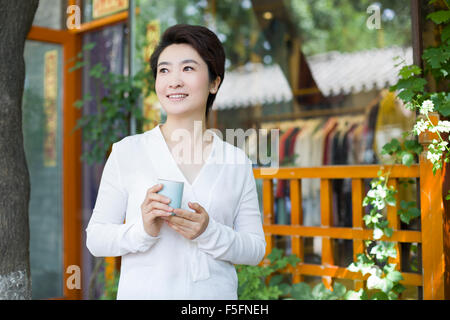 Frau Krämer in Tür mit einer Tasse Tee stehe Stockfoto