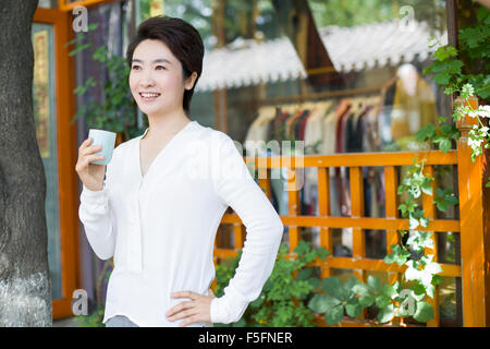 Frau Krämer in Tür mit einer Tasse Tee stehe Stockfoto