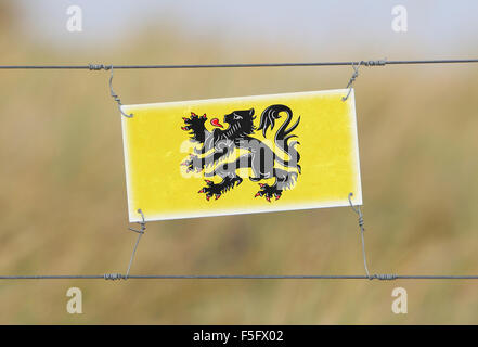 Grenze Zaun - alte Kunststoffschild mit einer Fahne - Flandern Stockfoto