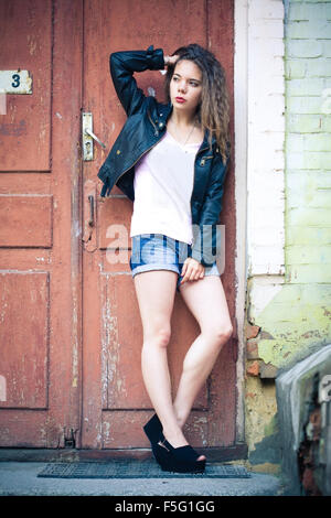 Junge Frau in Jeans-Shorts und Lederjacke Stockfoto