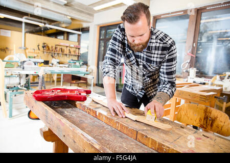 Tischler Schleifen eine hölzerne Gitarrenhals in Werkstatt Stockfoto