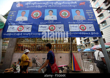 (151104)--YANGON, 4. November 2015 (Xinhua)--Menschen gehen vorbei an einem Wahlplakat der nationalen Einheitspartei in Yangon, Myanmar, 3. November 2015. Myanmar hat 8 November gesetzt, um die Parlamentswahlen 2015 bundesweit zu halten, die von insgesamt 6.065 Kandidaten mit 91 Parteien und 310 unabhängige Läufer ausgeführt werden.  (Xinhua/U Aung) Stockfoto