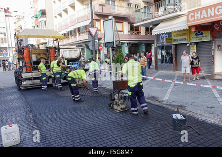 Spanischen Arbeiter bereiten eine künstliche Pflasterdecke Oberfläche mithilfe eines Rasters in weichen Asphalt gezwungen Stockfoto