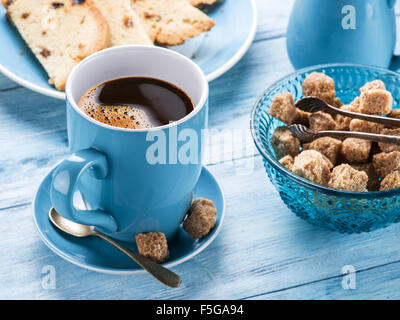 Tasse Kaffee, Milchkännchen, Rohrzucker Würfel und Obstkuchen auf alten Holztisch. Stockfoto