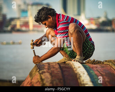 4. November 2015 - Dala, Yangon Division, Myanmar - ein Arbeiter Reparaturen den Rumpf des kleinen Holzfähre an den Ufern des Flusses Yangon in Dala, Yangon ist im Hintergrund. Dala befindet sich am südlichen Ufer von Yangon River gegenüber dem Zentrum von Yangon, Myanmar. Viele Burmesen Leben in Dala und umliegenden Gemeinden und in zentralen Yangon für Arbeit über den Fluss gehen. Vor dem 2. Weltkrieg hatte der Irrawaddy Flotilla Company seine wichtigsten Werften in Dala. Diese Tradition lebt weiter in die kleine Reparatur-Unternehmen die Arbeit an den Hunderten von kleinen Holzbooten, die als Pendler dienen für die Menschen o ferries Stockfoto