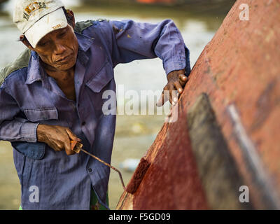 4. November 2015 - repaints Dala, Yangon Division, Myanmar - ein Arbeiter einen kleinen Holzfähre an den Ufern des Flusses Yangon in Dala. Dala befindet sich am südlichen Ufer von Yangon River gegenüber dem Zentrum von Yangon, Myanmar. Viele Burmesen Leben in Dala und umliegenden Gemeinden und in zentralen Yangon für Arbeit über den Fluss gehen. Vor dem 2. Weltkrieg hatte der Irrawaddy Flotilla Company seine wichtigsten Werften in Dala. Diese Tradition lebt weiter in die kleine Reparatur-Unternehmen die Arbeit an den Hunderten von kleinen Holzbooten, die als Pendler dienen für die Menschen in Yangon Fähren. Die Boote werden auf t hochgezogen Stockfoto