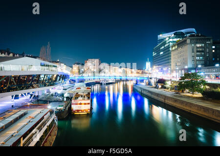 Moderne Gebäude und Boote über den Donaukanal in der Nacht, in Wien, Österreich. Stockfoto
